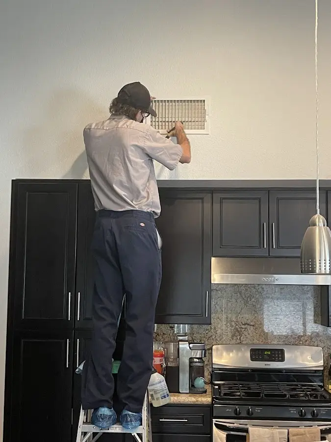 Technician inspecting an air vent during HVAC service in Suffern